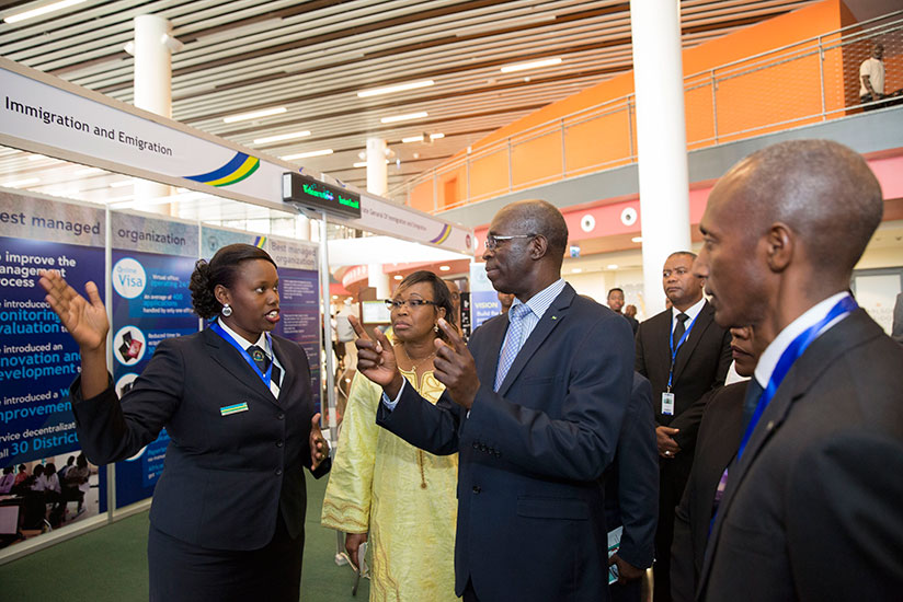 Prime Minister Anastase Murekezi (C) tours an exhibition stand of the Directorate of Immigration and Emigration on the sidelines of Africa Public Service Day conference at Kigali C....