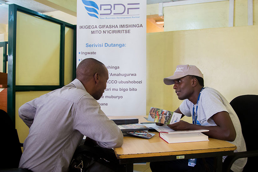 Mugisha (right) explains to Ndagijimana the services BDF offers. / Faustin Niyigena