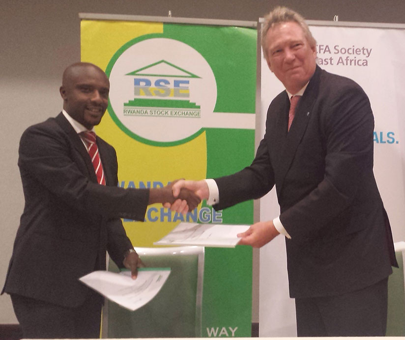 Rwabukumba (left) and Smith exchange the partnership deal documents on Wednesday. Under the agreement, the institute will build the capacity of financial market players. / Elisee Mpirwa