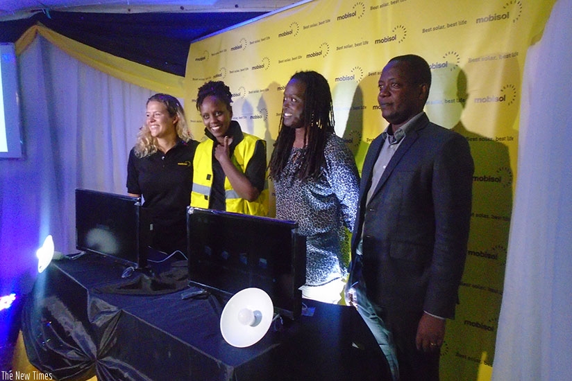Mobisol's Wintelmann (left) and Kamanzi are joined by other officials after the launch of the solar TV set. / Hudson Kuteesa. 