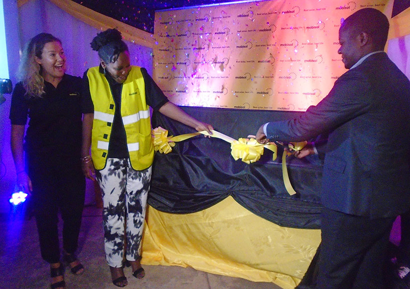 Kamanzi (right), Wintelmann and another Mobisol official launch the solar TV set on Wednesday. / Hudson Kuteesa