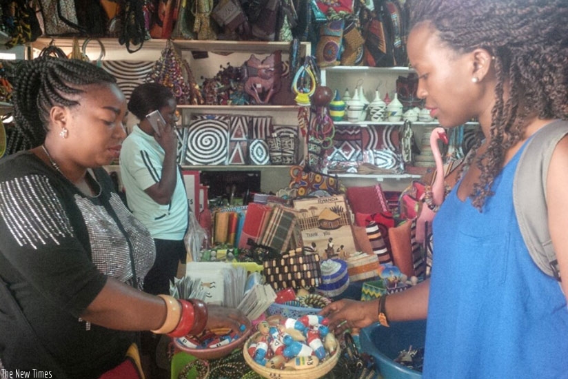 Uwamahoro (left) attends to a customer. The crafts dealer has added RPF paraphernalia to boost her earnings. / Joan Mbabazi