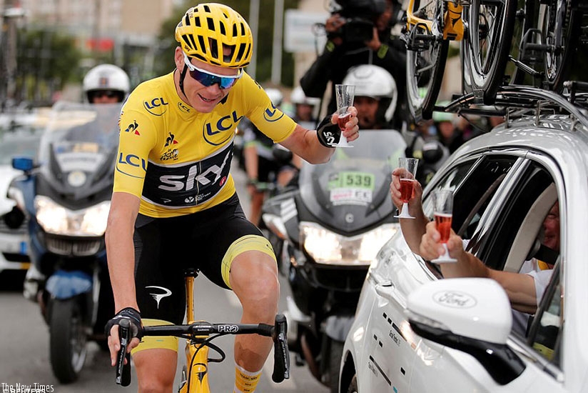 The 32-year-old winner takes a glass of champagne from his team during the processional final stage of the famous race. (Net photo)