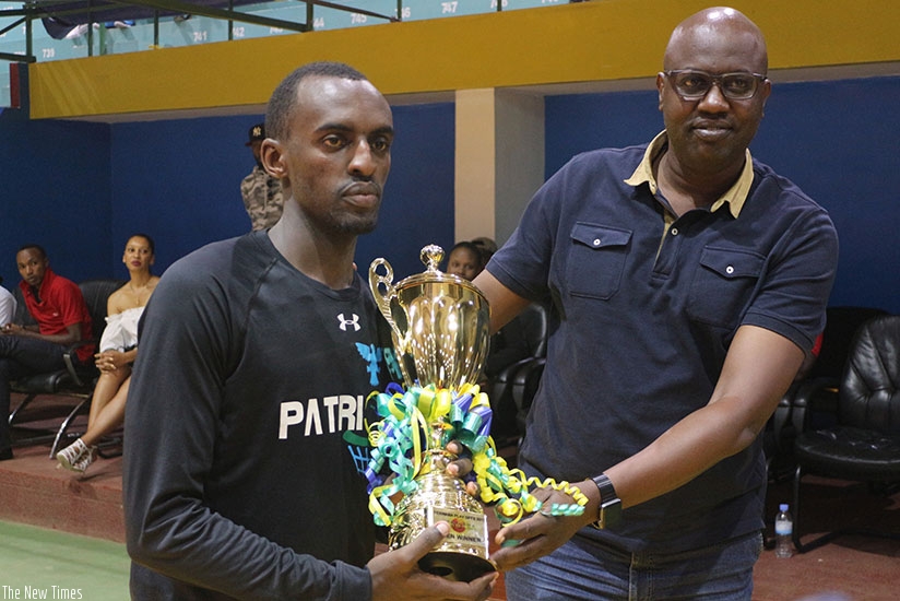 Aristide Mugabe receives the playoffs trophy from Ferwaba president Desire Mugwiza on Saturday after defeating REG. Courtesy