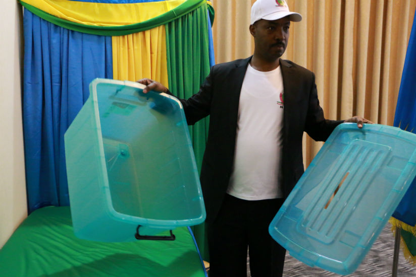 Kayonga displaying to the voters an empty ballot box before the elections began in China. / Courtesy