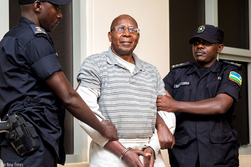Genocide suspect Leopold Munyakazi in the hands of Rwanda National Police officers upon arrival at Kigali International Airport after he was deported from the U.S last year. File.