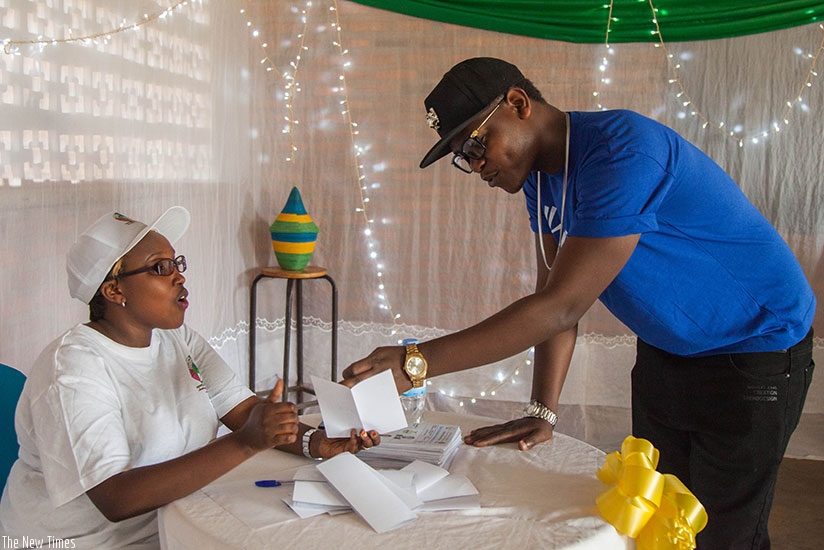 RnB crooner Bruce Melody shows his voter card to a polling agent atrnAPECA in Nyarugunga Sector where he exercised his civic right. N. Imbabazi.