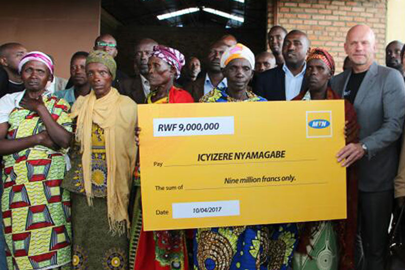 Hofker (right) hands over a dummy cheque to Genocide survivors in Nyamagabe District in April. The telecom firm was penalised in May by the regulator for non-compliance with licenc....