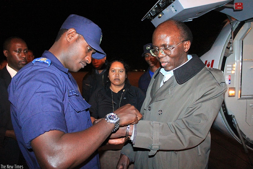 A Rwandan Security police officer handcuffs  Leon Mugesera on his arrival in 2012 at Kigali international Airport from Canada. He was last year sentenced to life in prison over his....