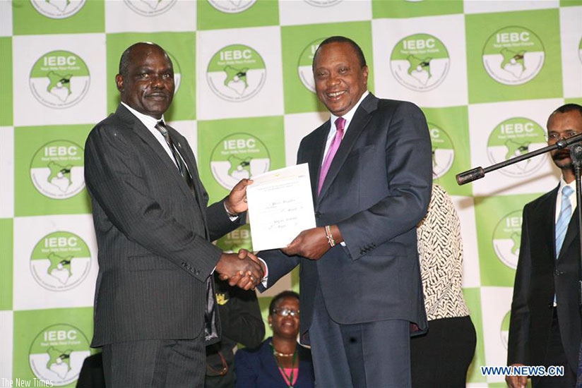 President Uhuru (R) receives the certificate as the winner of presidential elections from Independent Electoral and Boundaries Commission (IEBC) Chairman Wafula Chebukati (L, Front....