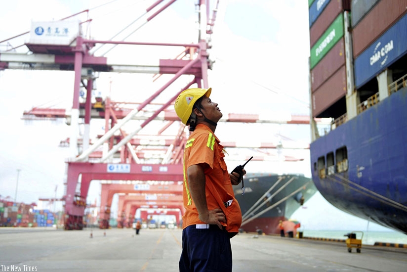 A worker watches as containers are loaded onto a ship in Qingdao in eastern China . Net.