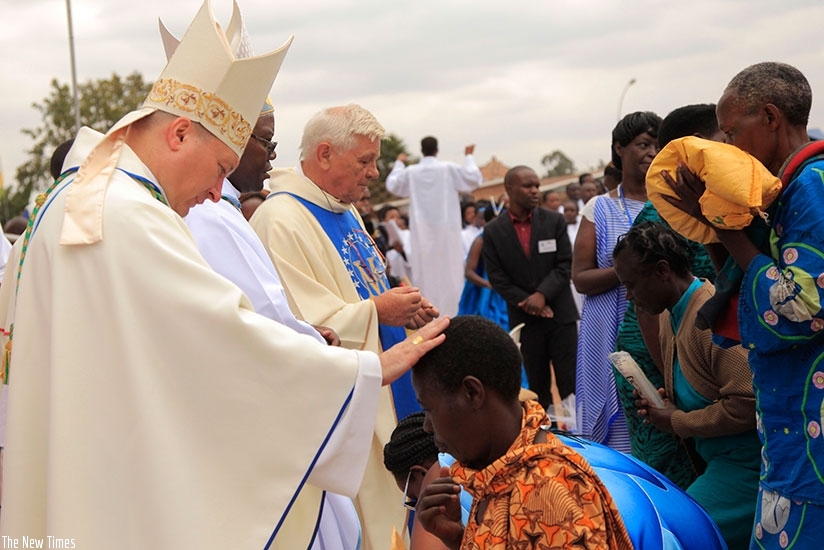Clerics bless Christians after giving their offerings during the Assumption Day mass at Kibeho on Tuesday. File