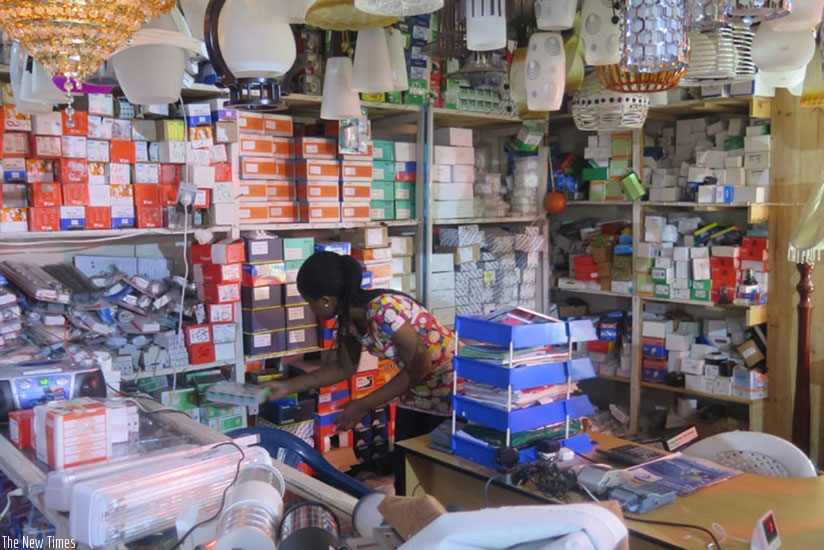 A businesswoman arranges commodities in her hardware shop in Kigali .  File
