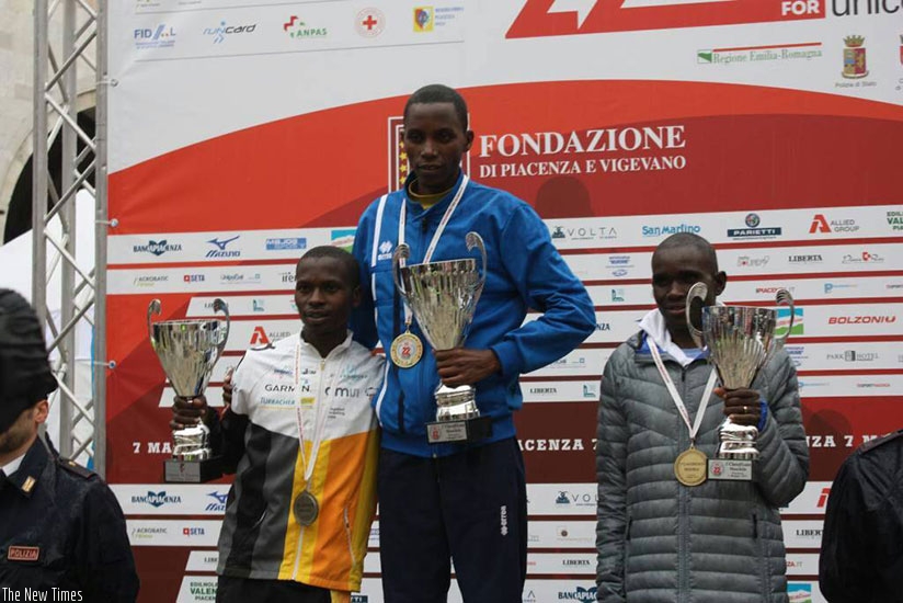 Felicien Muhitira (C) poses on the podium after winning a race in Piacenza, Italy. Courtesy