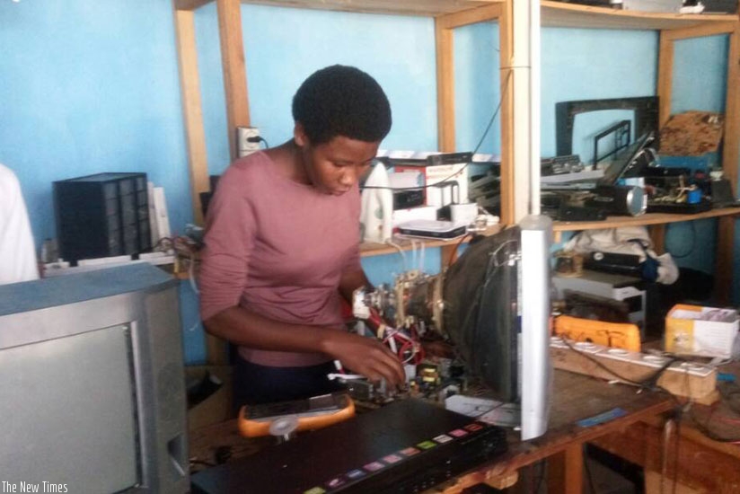 The entrepreneur repairs a TV screen at her workshop in Ruhango. Below is signpost of the services offered. / Photos: T. Kisambira