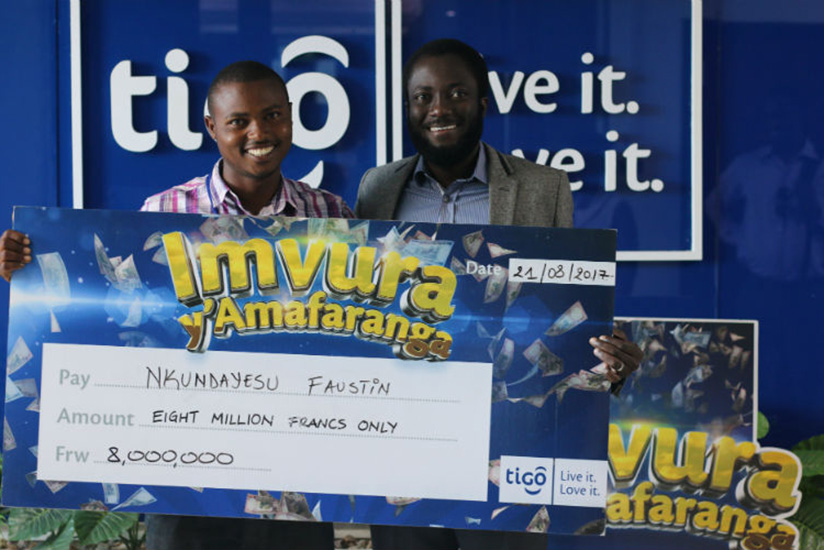 The Rwf5 million winner, Jean Pierre Usabuwera (left), receives a dummy cheque for the cash from Tigou2019s chief commercial officer, Yaw Ankoma Agyapong.  / Courtesy.