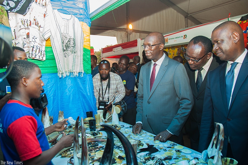 Prime Minister Anastase Murekezi (C), Trade and Industry minister Francois Kanimba (2nd R) and Private Sector Federation chairperson Benjamin Gasamagera visit one of the stands dur....