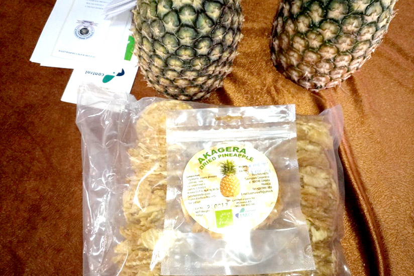 Sample of packaged dried pineapple apple which Tuzamurane Cooperative exports to France. In the background, there are two fresh raw pineapples. / Emmanuel Ntirenganya