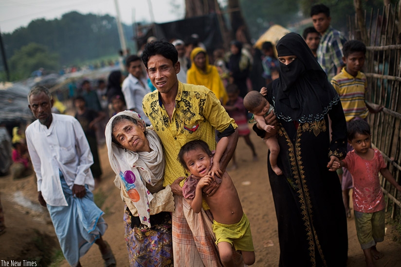 An exhausted Rohingya helps an elderly family member and a child as they arrive at Kutupalong refugee camp after crossing from Myanmar to the Bangladesh side of the border, in Ukhi....