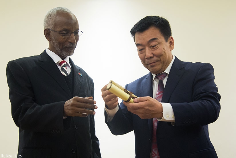 Xia gives a present to his counterpart Ngarambe in Kigali yesterday. / Timothy Kisambira