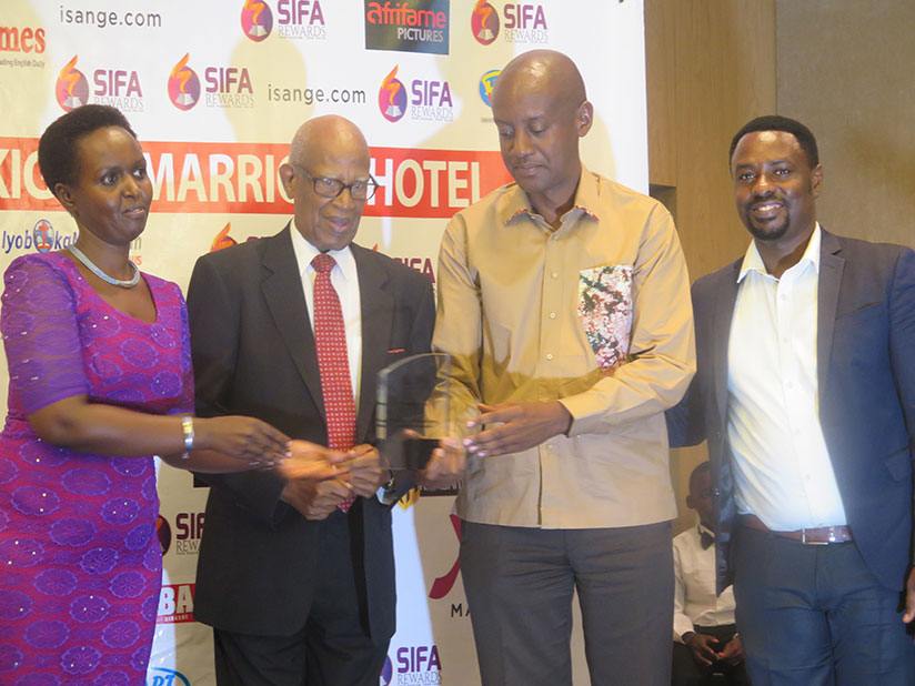 Cyprien Rugamba's son, Olivier Rugamba (R), receives the award on behalf of his father from Pastor Ezra Mpyisi at the Sifa Awards held in Kigali, Sunday. / Eddie Nsabimana