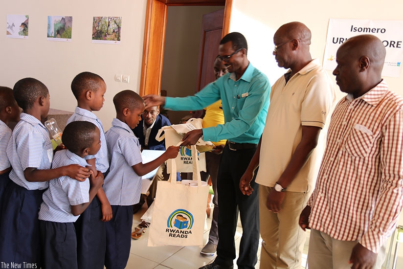 Karongi Environment Museum manager Andru00e9 Ndabaga, flanked by Edition Bakame officials, rewards children after a reading competition at the museum. (M. Nkurunziza)