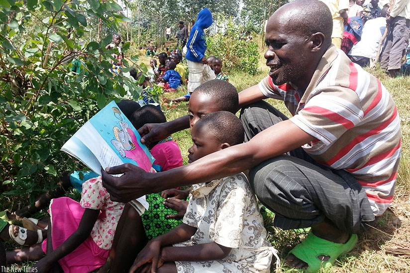 A volunteer helps children to read in Nyange, Ngororero on September 30.  (Marie Anne Dushimimana)