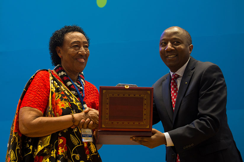 Premier Dr Ngirente (R) awards Francoise Nyirantagorama of Ecole La colombiere an award during the Taxpayeru2019s Day in Kigali yesterday. Timothy Kisambira. 