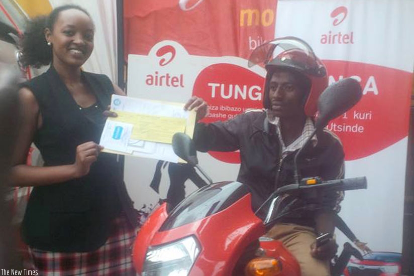 Twiringiyima receives the bike and ownership documents from Munganyinka. / Joan Mbabazi.