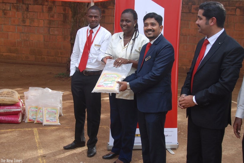 Naghoor (second right) hands over some of the food items to Umurangwa as UAE Exchange staff look on .  (P. Tumwebaze)