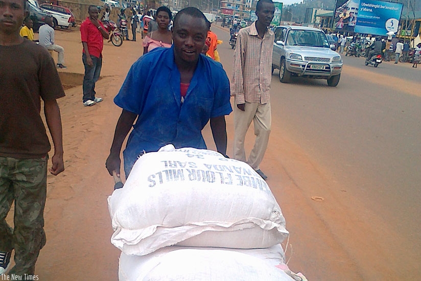 A casual labourer pushes load on a wheelbarrow in Nyabugogo. Timothy Kisambira.