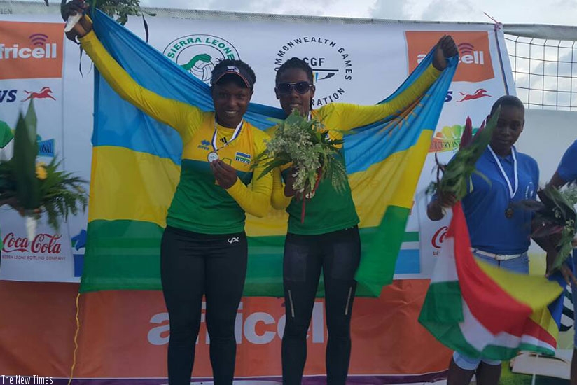 Charlotte Ndayisenga and Denyse Mutatsimpundu pose on the podium with their gold medals and the Rwandan flag. (Courtesy)