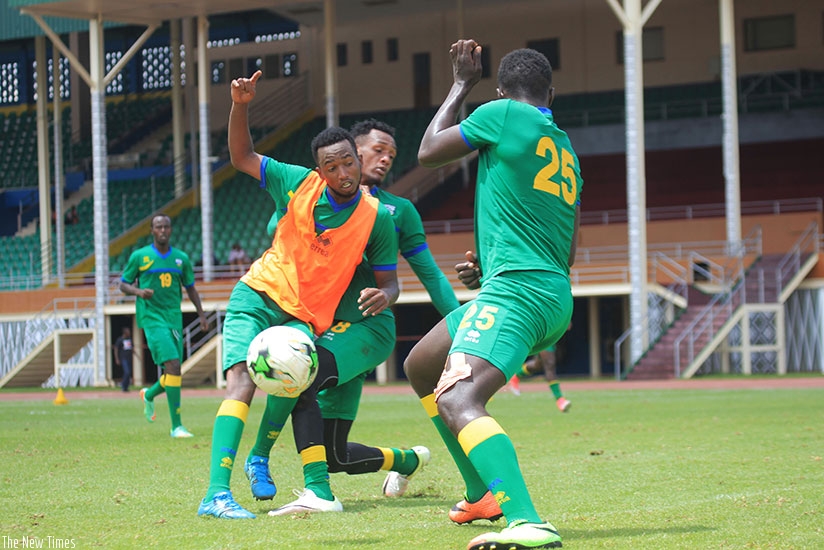 Striker Justin Mico is tackled by midfielder Ally Niyonzima as defender Yves Rugwiro closes in during Amavubi training at Amahoro Stadium on Tuesday. (Sam Ngendahimana)