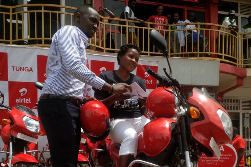 Gatera helps Uwanyirigira to put on a helmet after receiving the bike. / Joan Mbabazi.