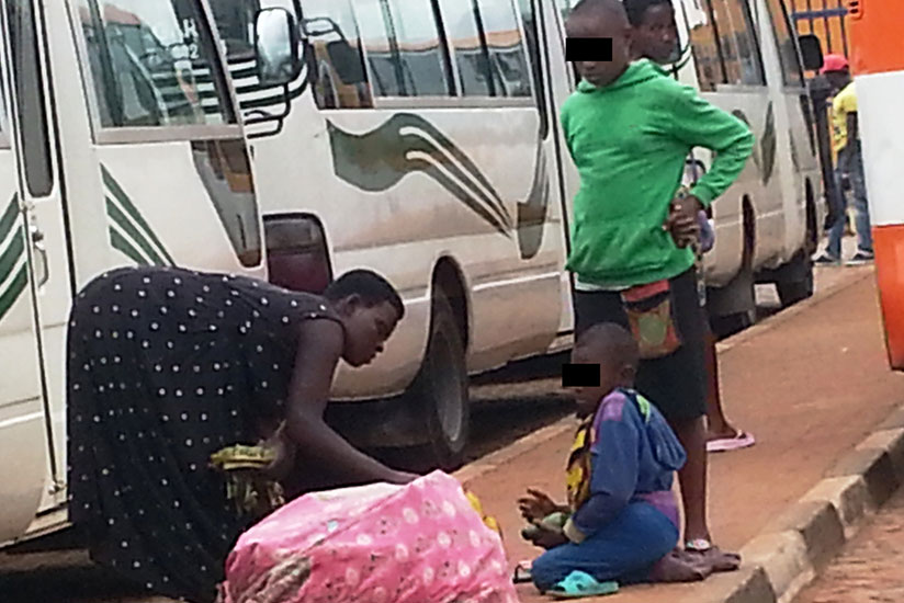 Pascal (not real name), the disabled 8-year-old boy, begs a fruit vendor at Kimironko taxi park as his 11-year-old sister looks on. (Photos by Marie Anne Dushimimana)