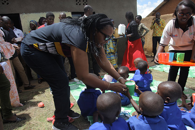 Minister Nyirasafari gives milk to children during the event in Huye District. Courtesy. 
