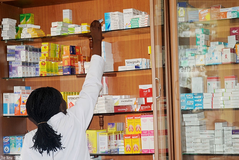 A pharmacist arranges drugs on the shelf.. File.
