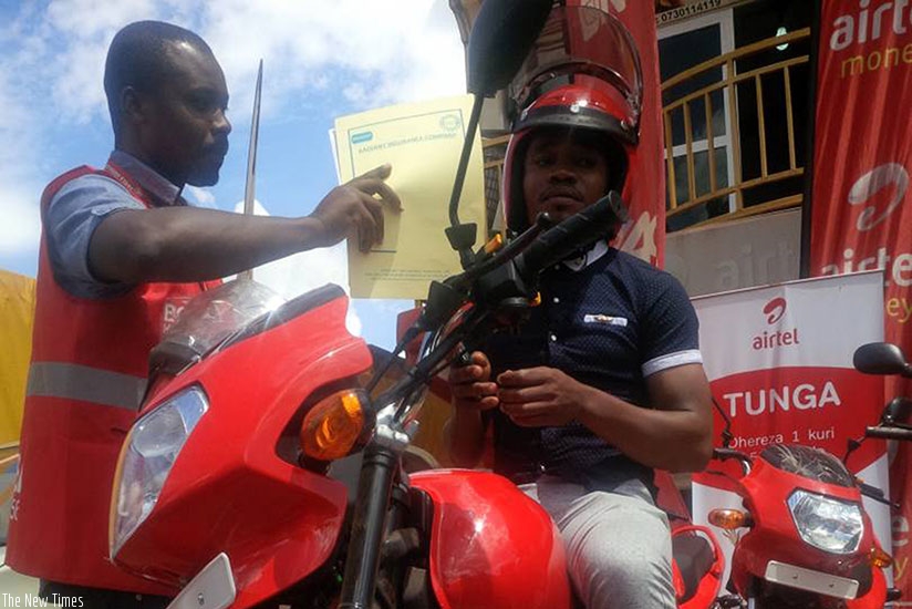 Nsabimana (right) receives the motorcycle and documents on Thursday. / Joan Mbabazi.