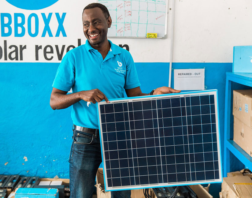 A BBOXX employee displays a solar panel in rural Rwanda. / Courtesy
