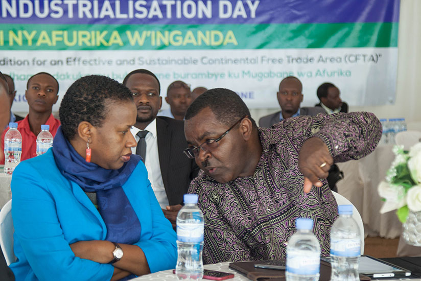 Vincent Munyeshyaka, the minister for trade and industry (R), chats with Fanfan Rwanyindo, the minister for public service and labour, during the celebration of African Industriali....