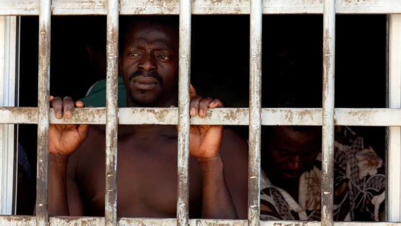 A migrant looks out of a barred door at a detention centre in Gharyan, Libya, Oct. 12, 2017. Hundreds more like him are being kept in smuggler-owned Libyan warehouses, where they a....