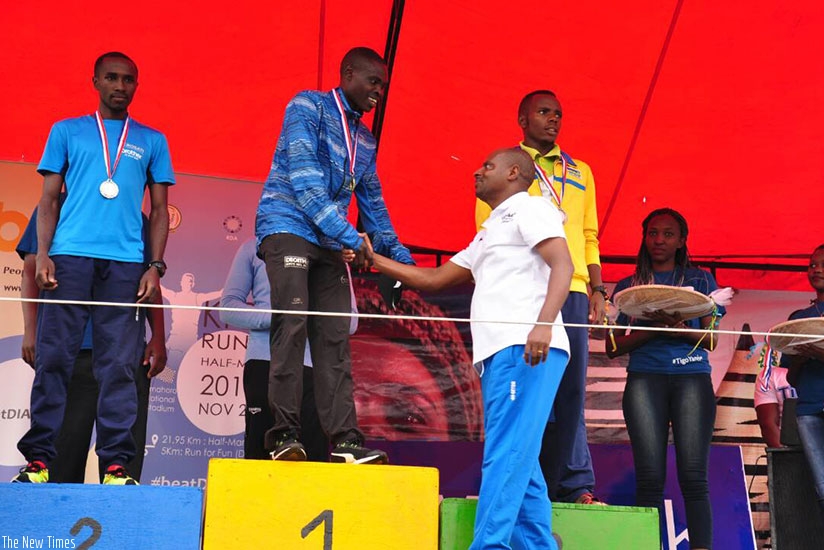 The president of Rwanda Athletics Federation Jean Paul Munyandamutsa congratulates Noel Hitimana while Salome Nyirarukundo (right) crosses the finish line. Peter Kamasa.