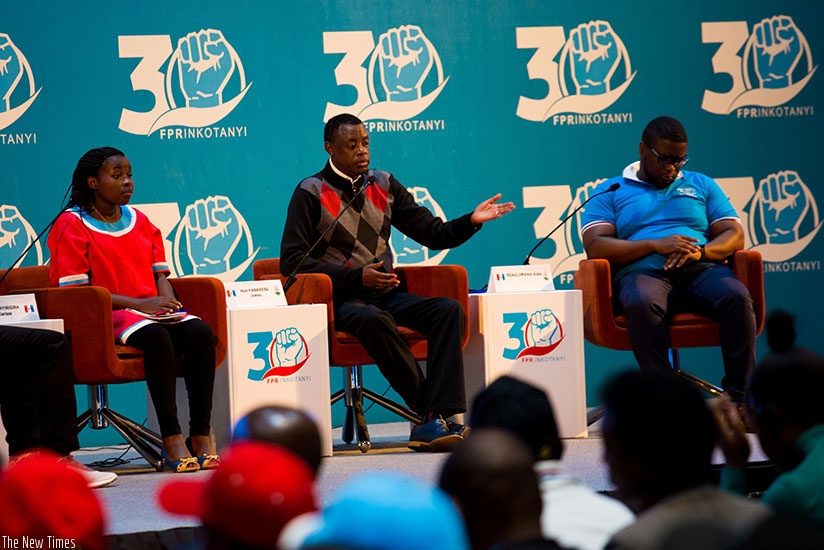 Defense minister James Kabarebe (C) speaks at the Rwanda Patriotic Front youth league congress as Clarisse Uwanyirigira (L), a youth leader, and Alain Ndagijimana, an entrepreneur ....
