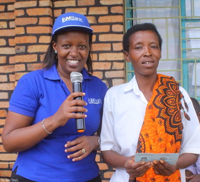 One of the beneficiaries after receiving her medicare insurance card from I&M Bank HR manager, Diana Kwarisima. / Kelly Rwamapera