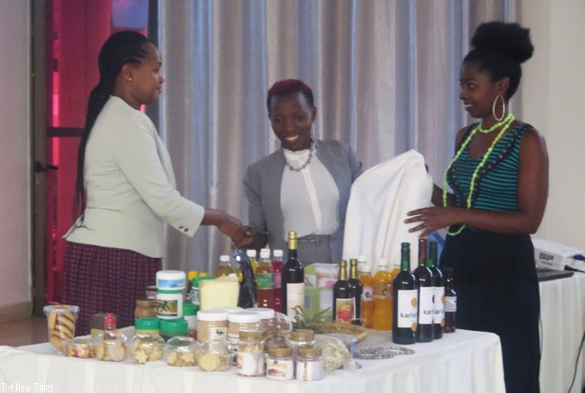 Mbabazi (left) checks out some of the products made by young agro-processors at the workshop. / Michel Nkurunziza