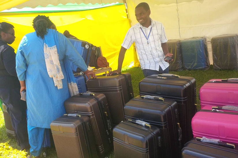 Salesmen try to convince a client to buy a suitcase.  / Joan Mbabazi.