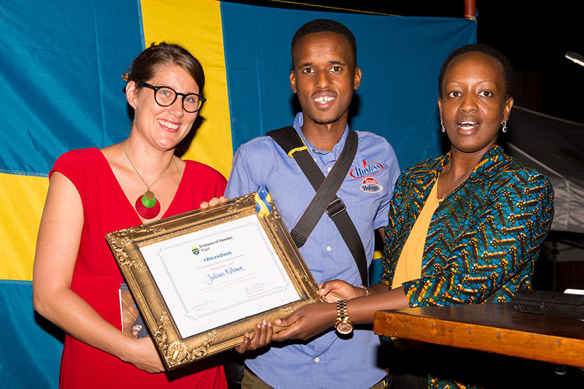 Sweden's envoy to Rwanda Jenny Ohlsson and PS at MIGEPROF Nadine Umutoni award Julius Ntare the winner of a photo-exhibition entitled 'Swedish Dads' and 'Rwandan Dads' that feature....