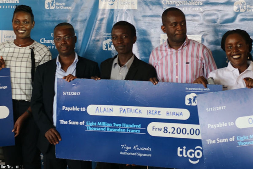 Hirwa (middle) receives a dummy cheque of his prize money from Amoateng (second left) and Reach for Change's Madzima-Bosha (right). Left is ICT ministry's Irere.   / Joan Mbabazi.