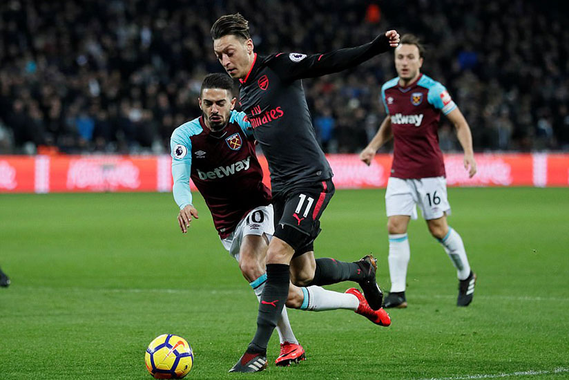 Arsenal playmaker Mesut Ozil takes the ball past West Ham attacking midfielder Lanzini as he tries to spark an attack. / Net photo