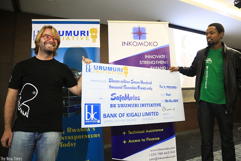 Officials from SafeMotos, Barrett Nash (left) and Eric Joseph, display a dummy cheque for the Rwf11.7 million interest-free loan they won in the BK Urumuri Initiative competition. ....